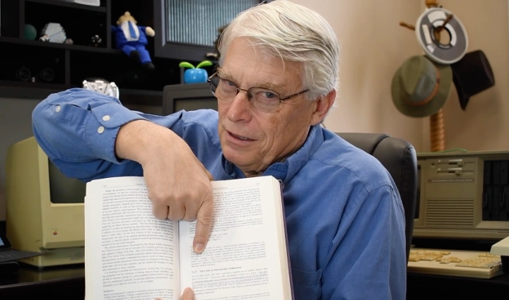 رابرت سی. مارتین، نویسنده کتاب Clean Code، در حال اشاره به بخشی از متن کتاب در دفتر کار خود