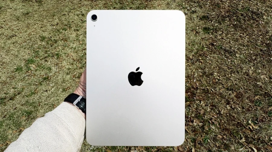 نمای پشت iPad 2025 رنگ نقره‌ای در فضای باز، در دست کاربر