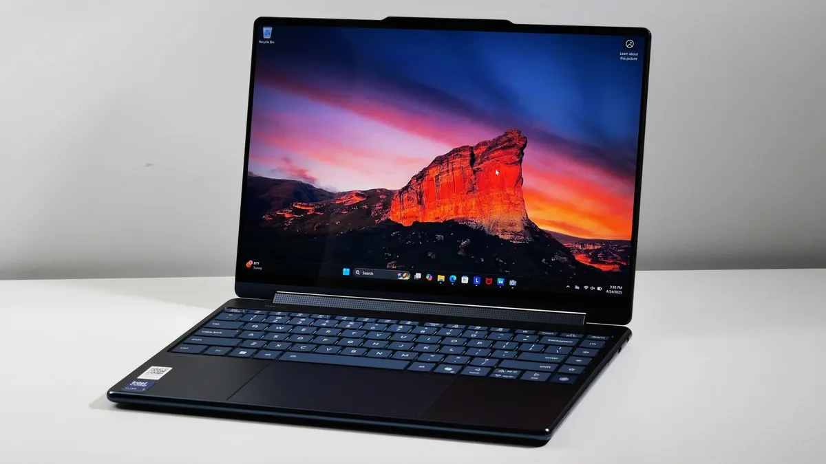 لپ‌تاپ Lenovo Yoga 9i Aura Edition باز شده روی میز با صفحه‌نمایش OLED روشن