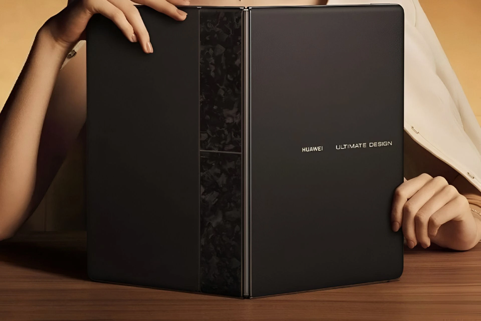 نمای پشت لپ‌تاپ تاشوی هواوی MateBook Fold Ultimate Design با لوگوی طلایی HUAWEI و ULTIMATE DESIGN در حال بسته بودن روی میز چوبی