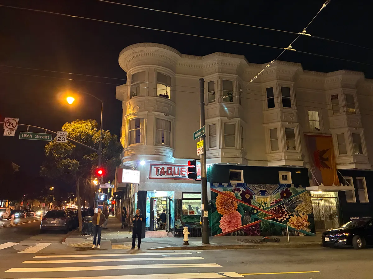 نمونه عکس شبانه با آیفون 16e؛ خیابانی با چراغ‌های روشن و نمای واضح ساختمان در تاریکی