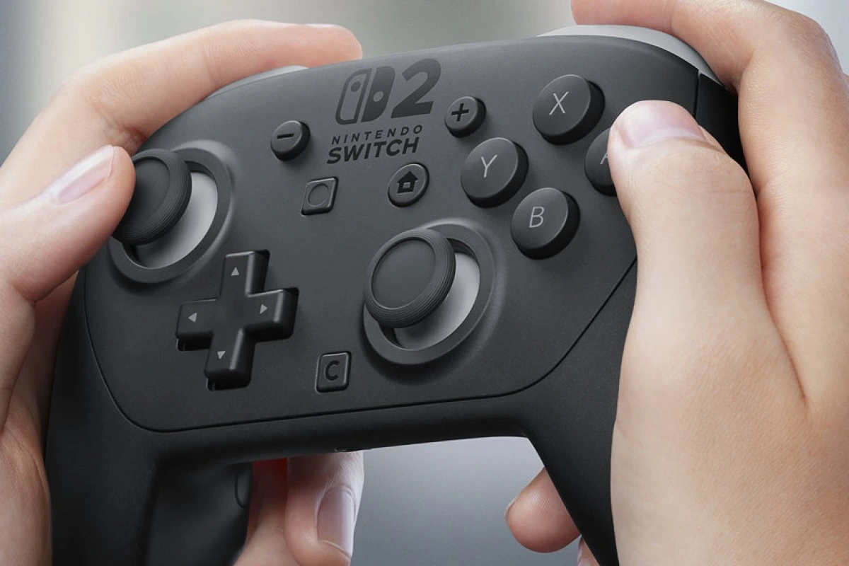 نمای نزدیک از دسته بازی Pro Controller جدید Nintendo Switch 2 که در دست یک فرد قرار دارد و دکمه‌ها و جوی‌استیک‌ها به وضوح دیده می‌شوند